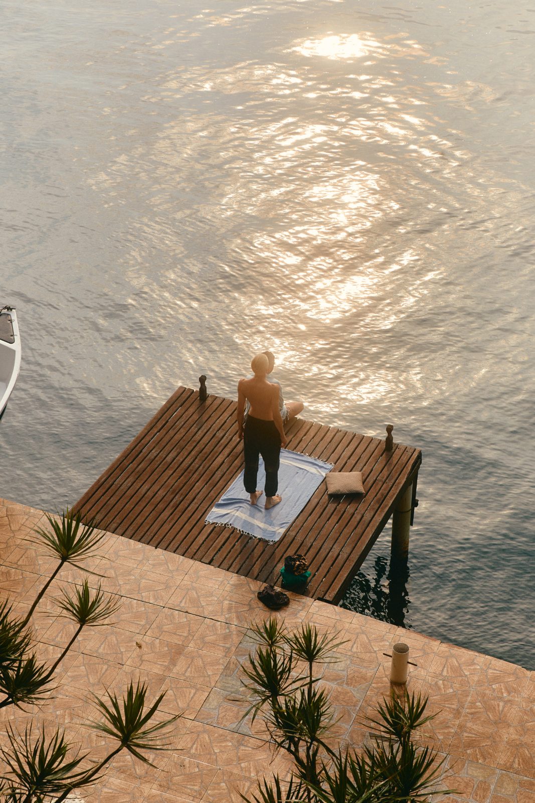 two figures on a jetty over golden water at first light