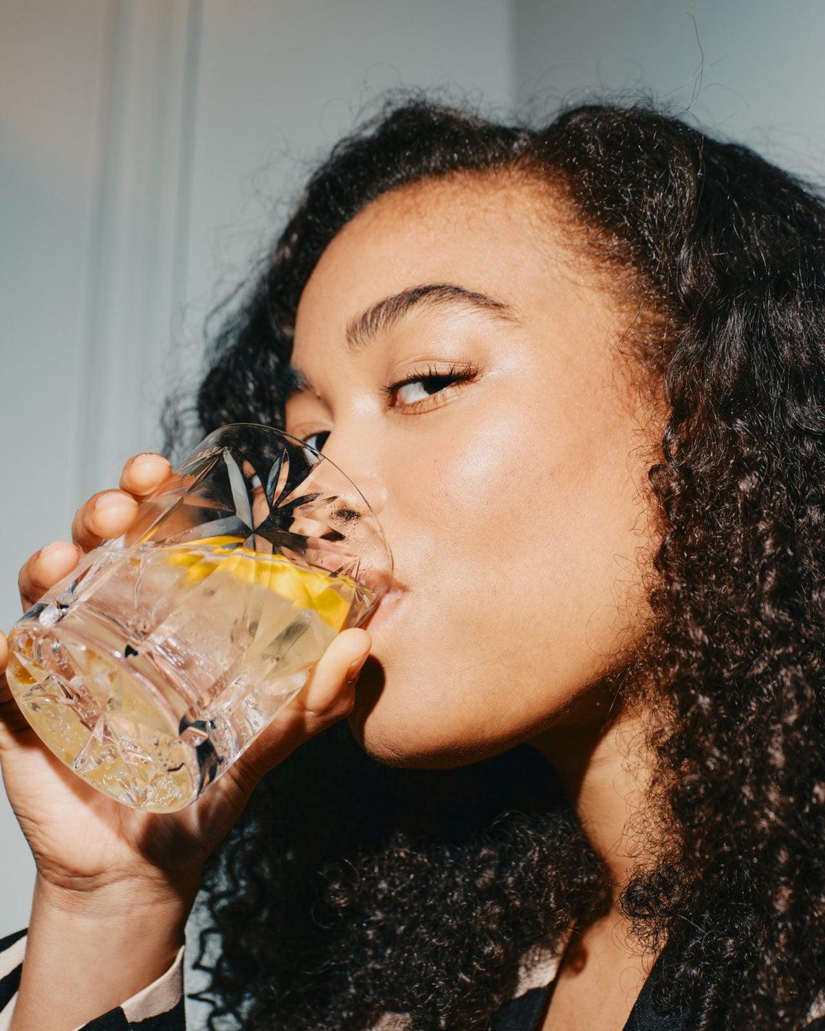 a woman drinking from a cut-glass tumbler